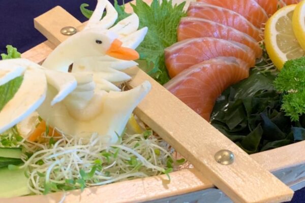 Salmon sashimi platter served in a traditional wooden boat tray by Ramen Tekapo